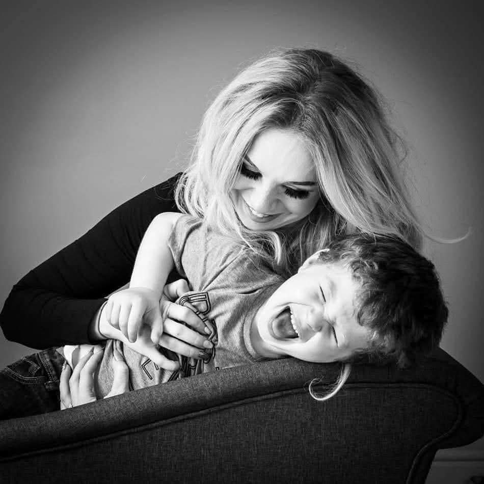 Hannah laughing with her eldest son on a sofa — black and white photograph