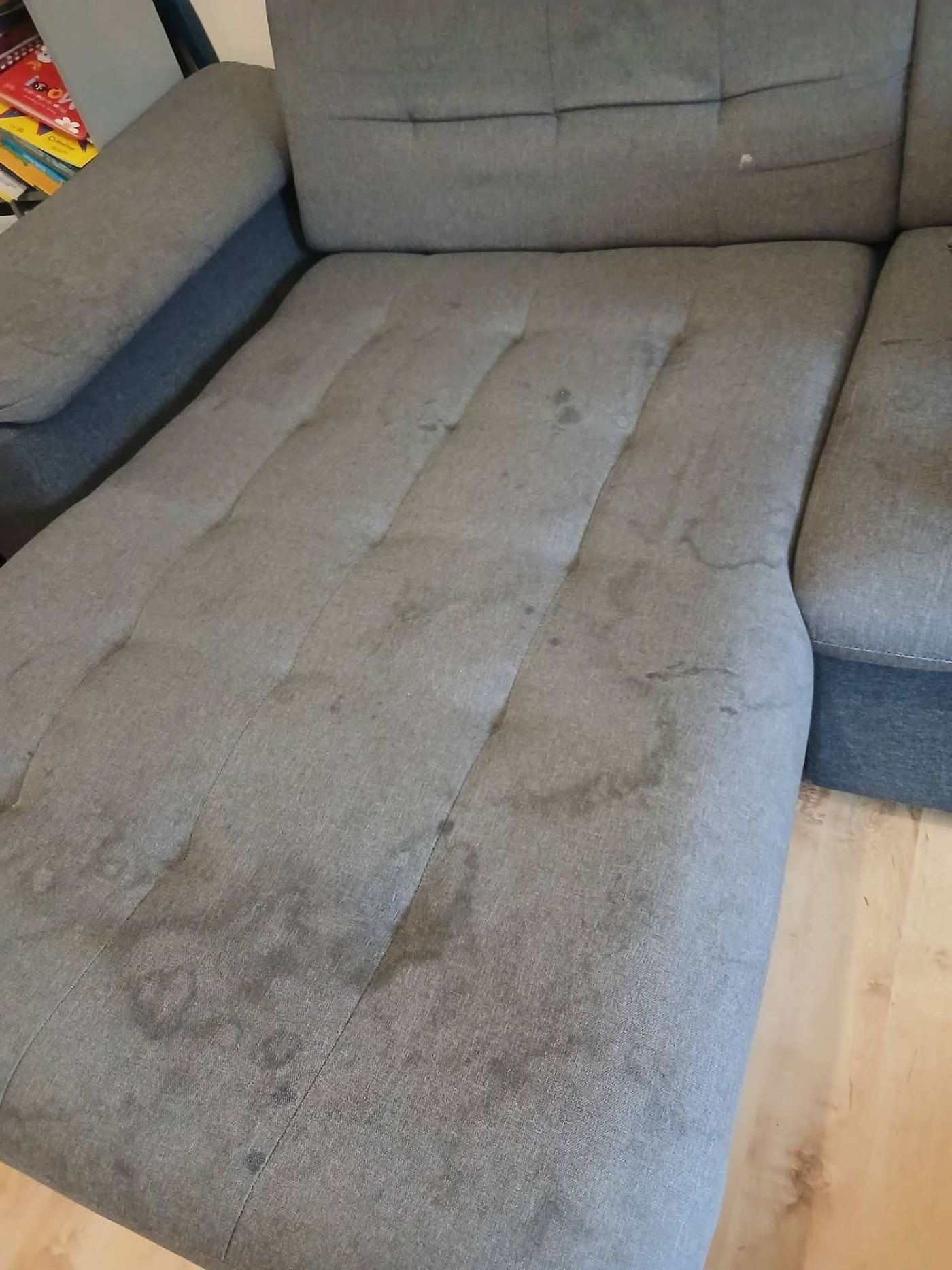 Grey fabric sofa with visible stains and water marks before cleaning