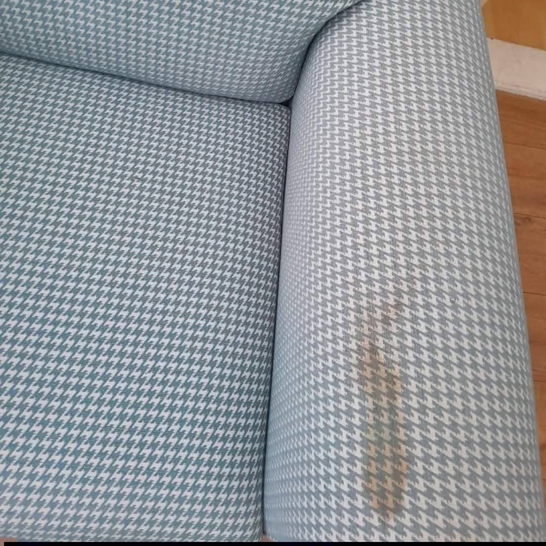 Houndstooth fabric sofa arm with brown stain before cleaning