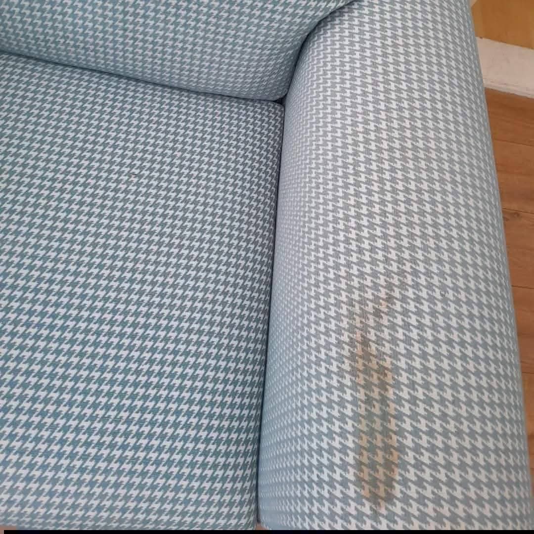 Houndstooth fabric sofa arm with brown stain before cleaning
